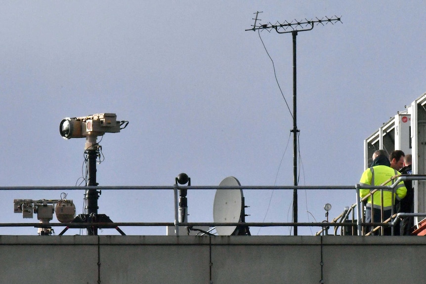 Technical equipment on a roof is silhouetted against the sky.