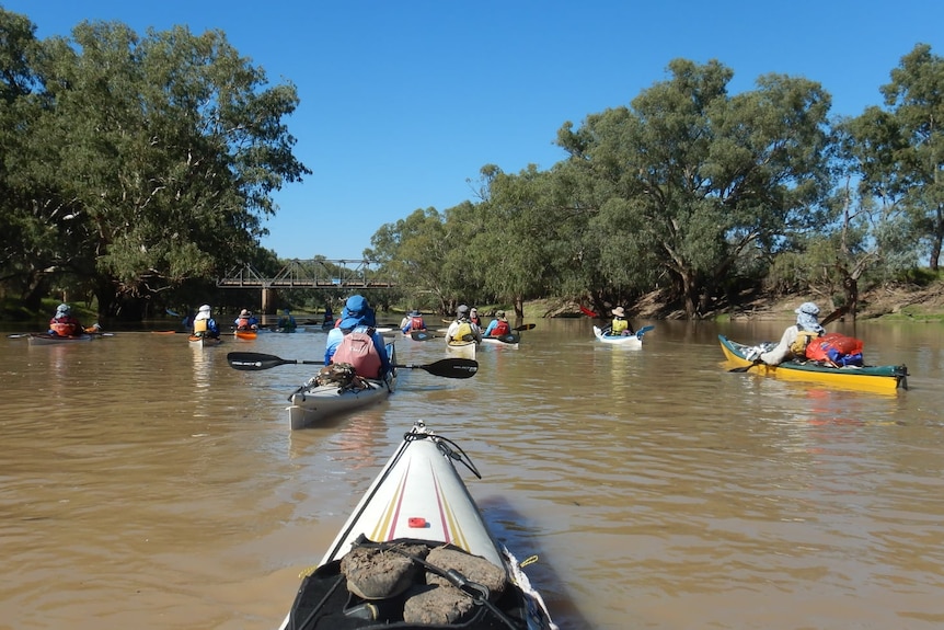 kayakers on a river heading toward a bridge