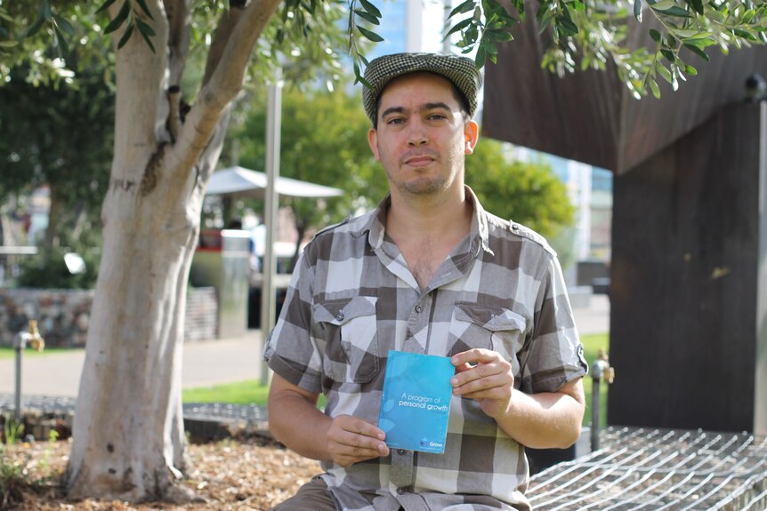 Man standing holding small blue book 