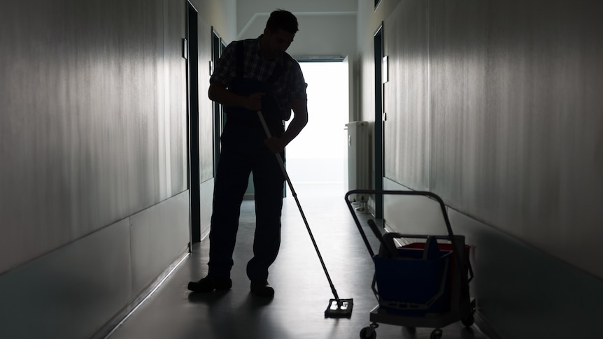 A silhouette of a cleaner mopping a floor.
