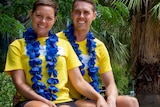 A young couple in matching cancer council t-shirts sitting outside on a metal chair.