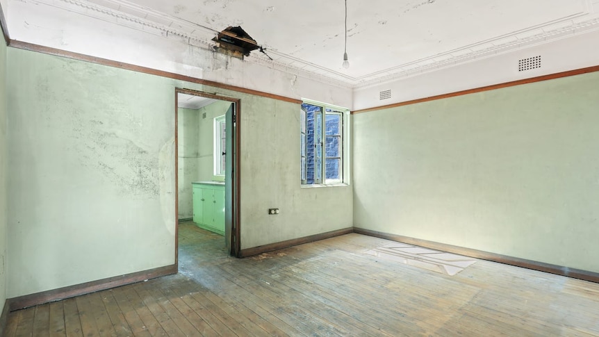 A bare room with a wood floor and a hole in the ceiling 