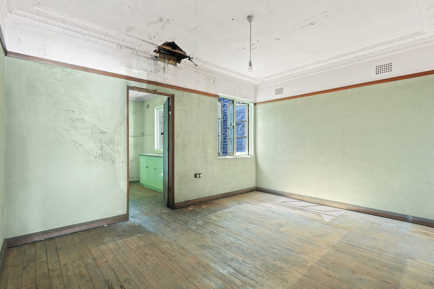 A bare room with a wood floor and a hole in the ceiling 