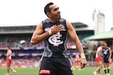 AFL player with his hand on his chest after scoring a goal during a match
