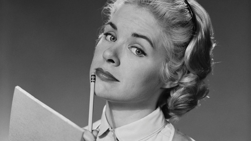 1950s woman with blonde hair and a note pad and pencil thinking