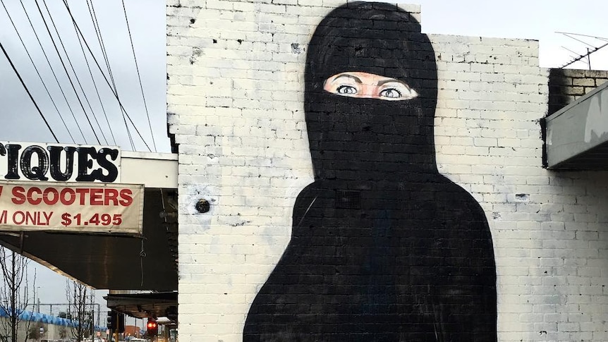 Mural of Hillary Clinton on the side of a building wearing a burqa.