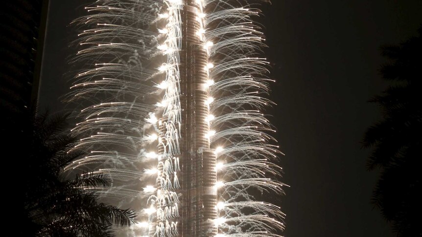 Fireworks coloured white explode all the way up each side of the Burj Khalifa.