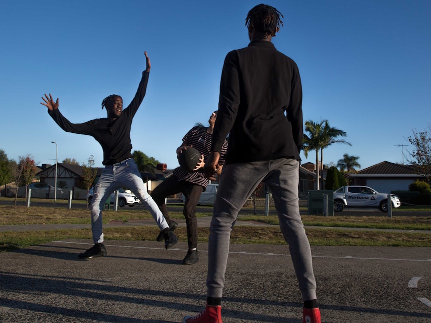 Mohamed and his friend play with another boy on the suburban basketball court.