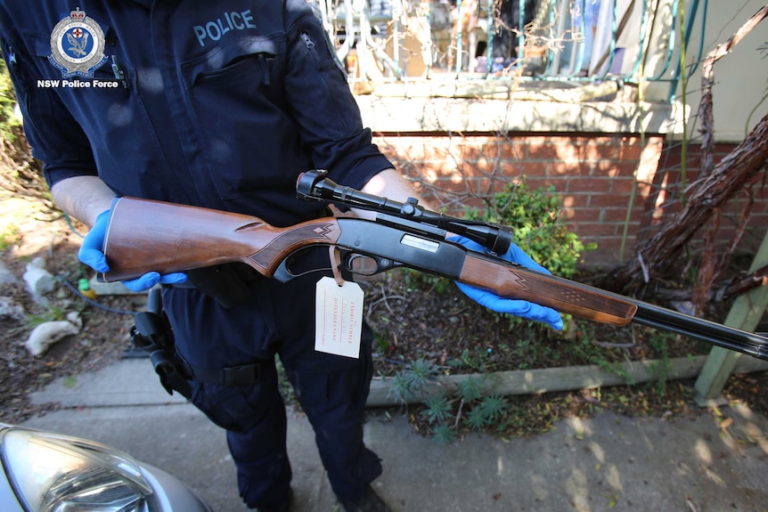 A law enforcement officer displays a weapon connected to illegal narcotic activities.