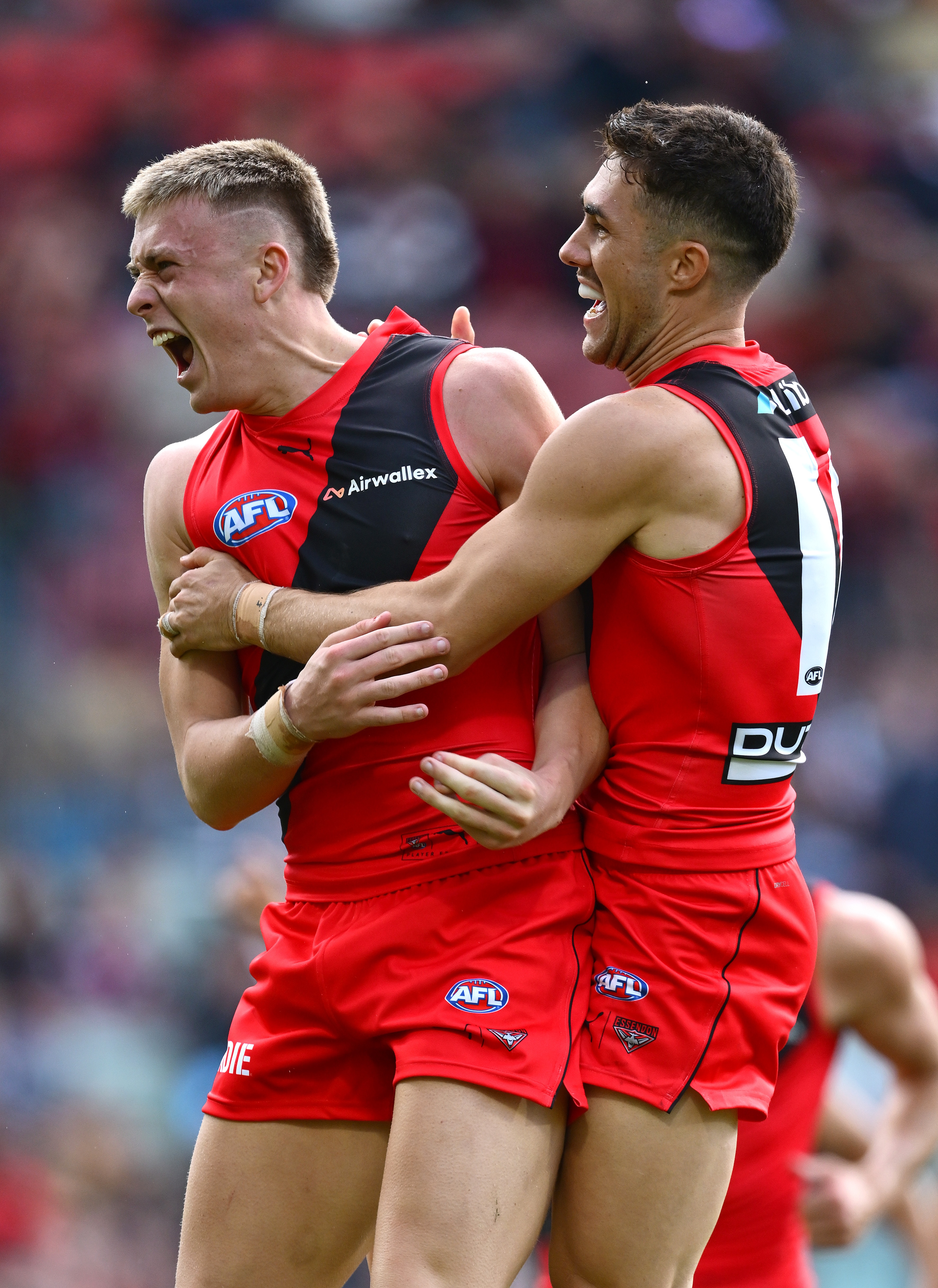 Two Essendon AFL players celebrate a goal against Melbourne.