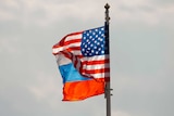 A US and Russian flag wave on the wind next to each other.