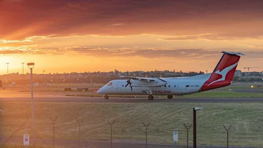 A Qantas plane parked outside an airport at sunset