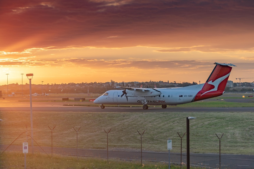 A Qantas plane parked outside an airport at sunset