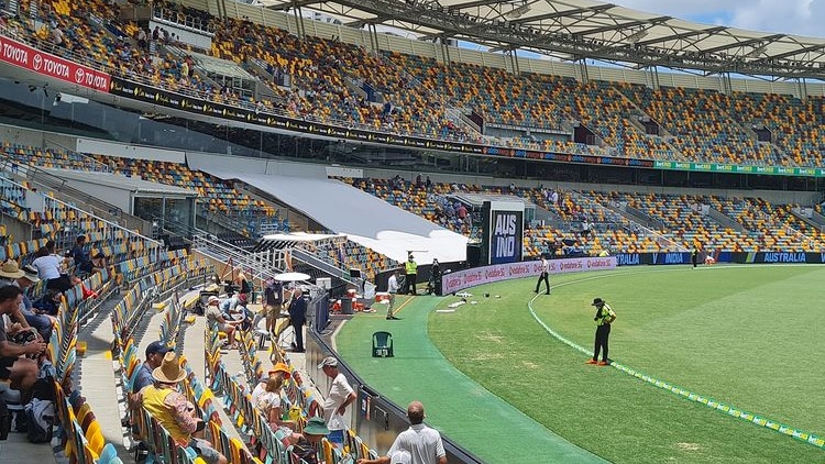 Security guards stand on the boundary line as a few dozen spectators look on at the Gabba.