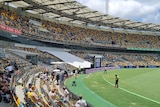 Security guards stand on the boundary line as a few dozen spectators look on at the Gabba.