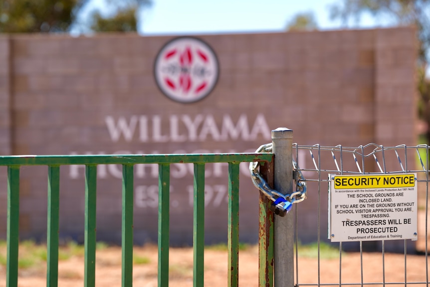 A lock wrapped around a green gate at Willyama High School in Broken Hill next to a security notice. 