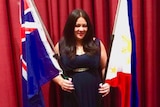 Carmen Garcia stands in a dark gown, smiling holding the Australian and Philippines flags.