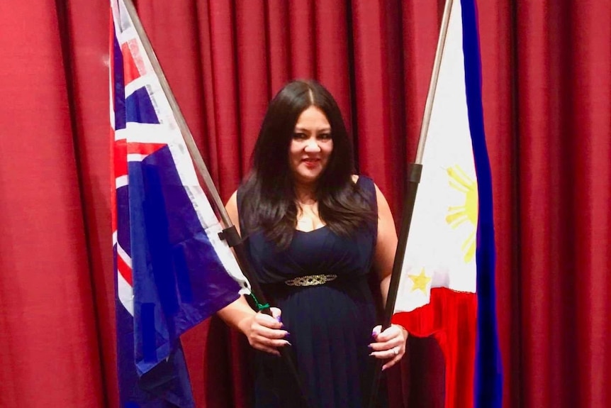 Carmen Garcia stands in a dark gown, smiling holding the Australian and Philippines flags.