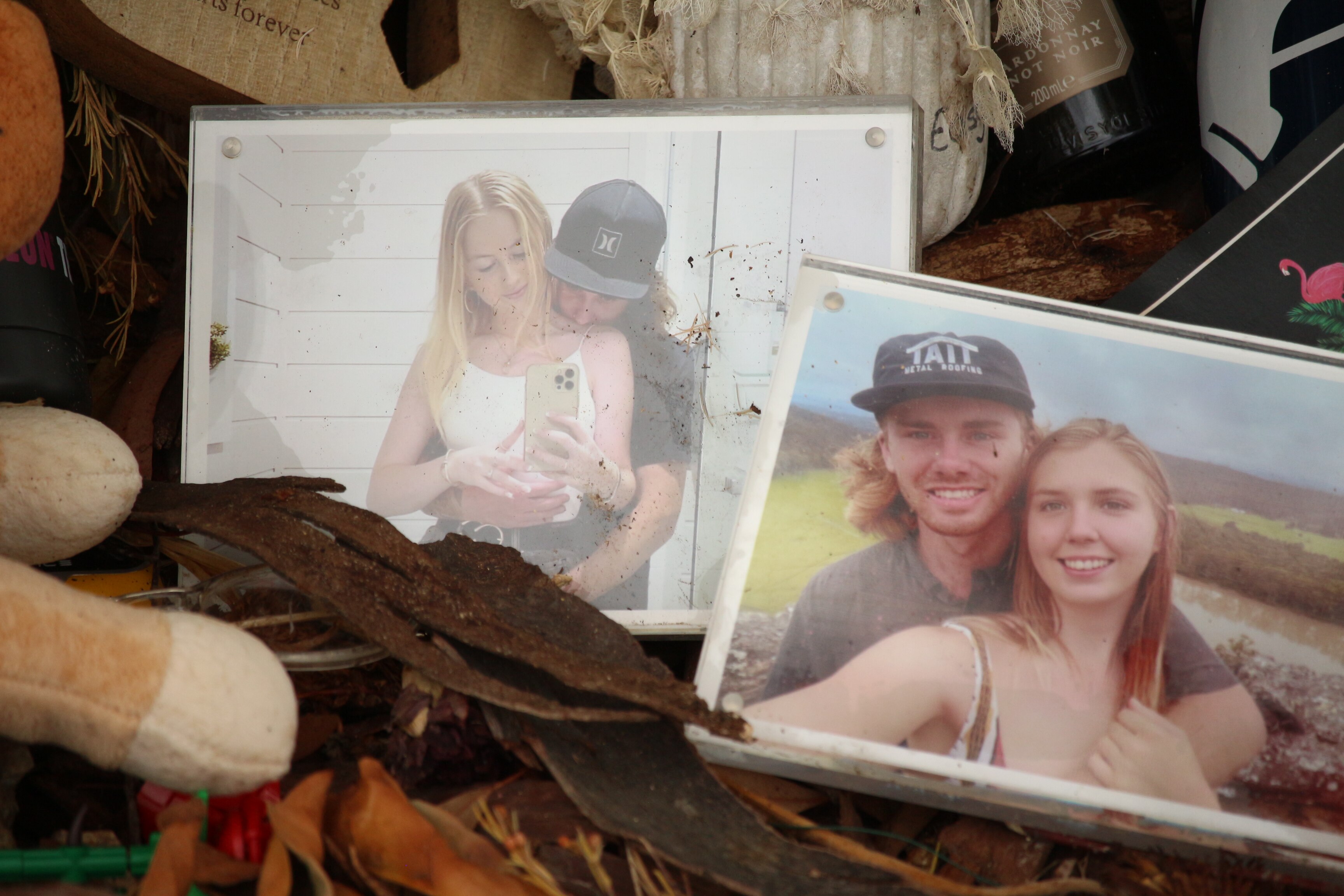 Sobre el tronco de un árbol hay dos fotografías enmarcadas de dos grupos diferentes de hombres jóvenes abrazando a dos mujeres jóvenes diferentes.