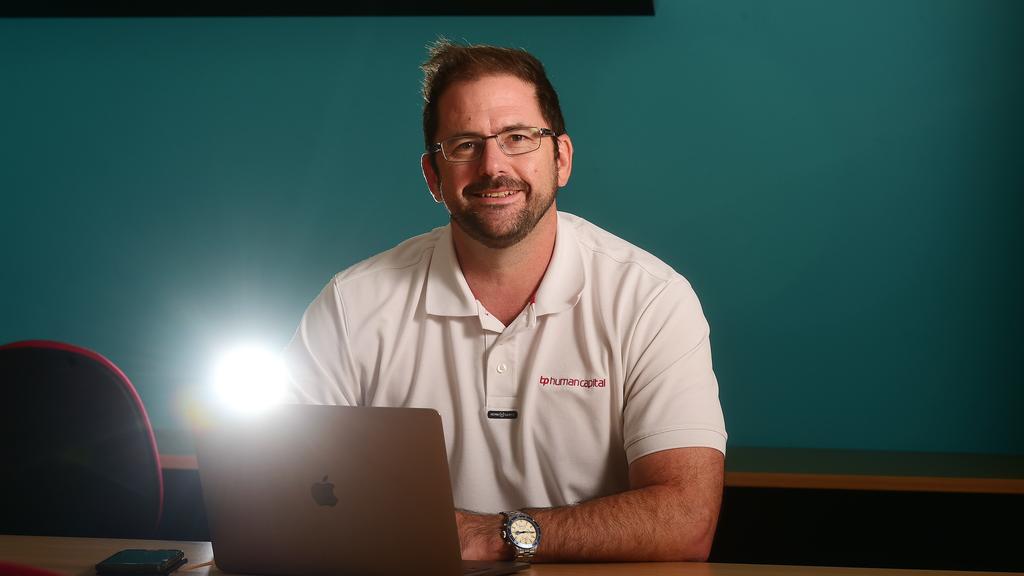 Man in white polo shirt sitting a desk behind his computer