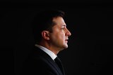 A side angle portrait of Volodymyr Zelenskyy's face with a black background filling the space around him