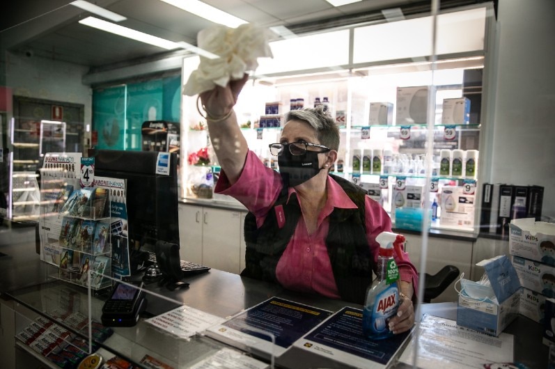 A worker cleaning down a screen at Barone Pharmacy.