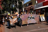 Women marching in central Alice Springs with banners protesting against violence.