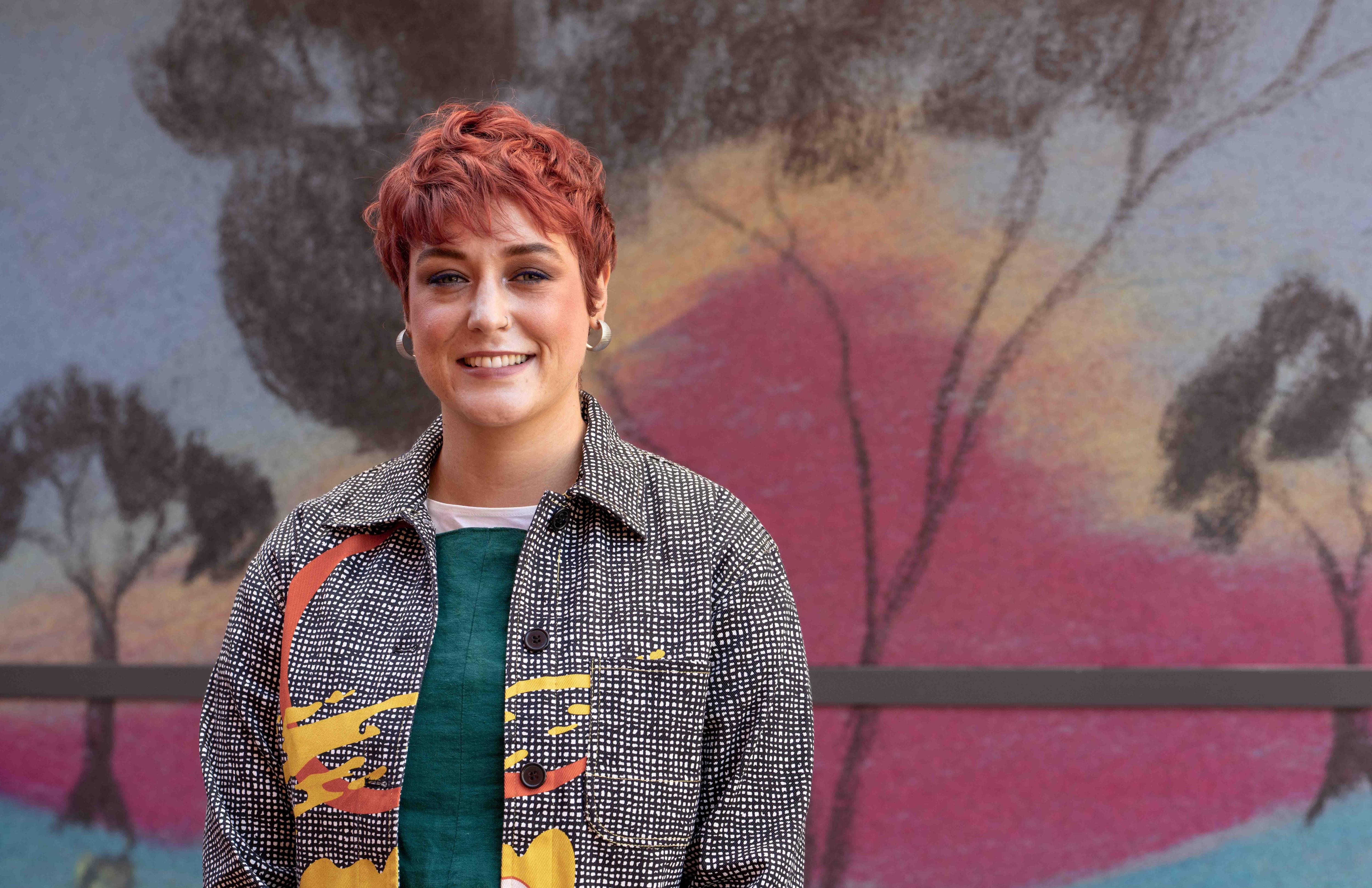 Foto média de uma mulher em frente a um mural.