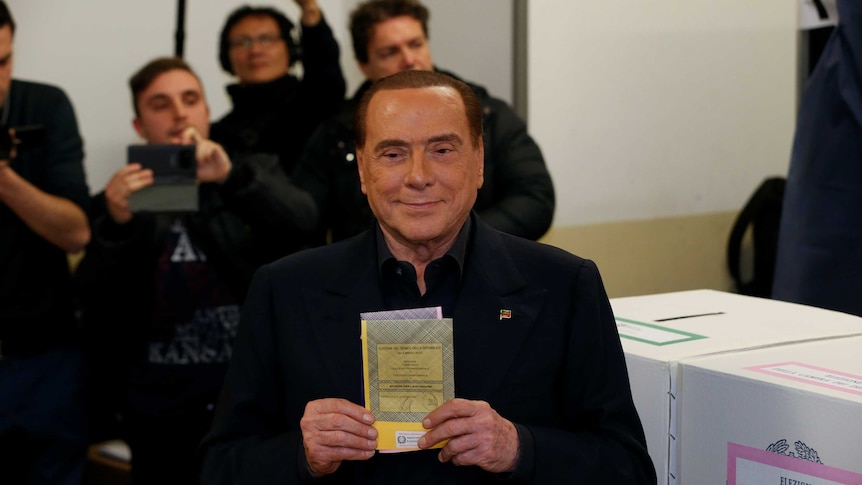 Man holds a ballot paper in front of his chest