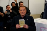 Man holds a ballot paper in front of his chest