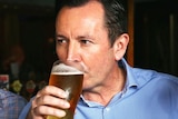 A tight crop of Mark McGowan drinking a pint of beer