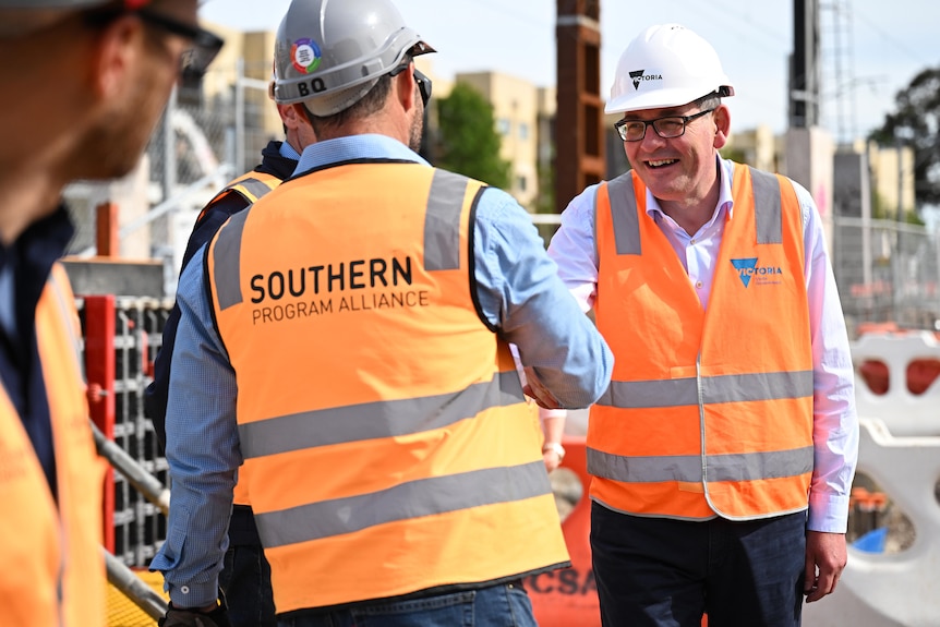 Victorian premier Daniel Andrews shakes hands with a person wearing a hard hat and a high-vis vest.