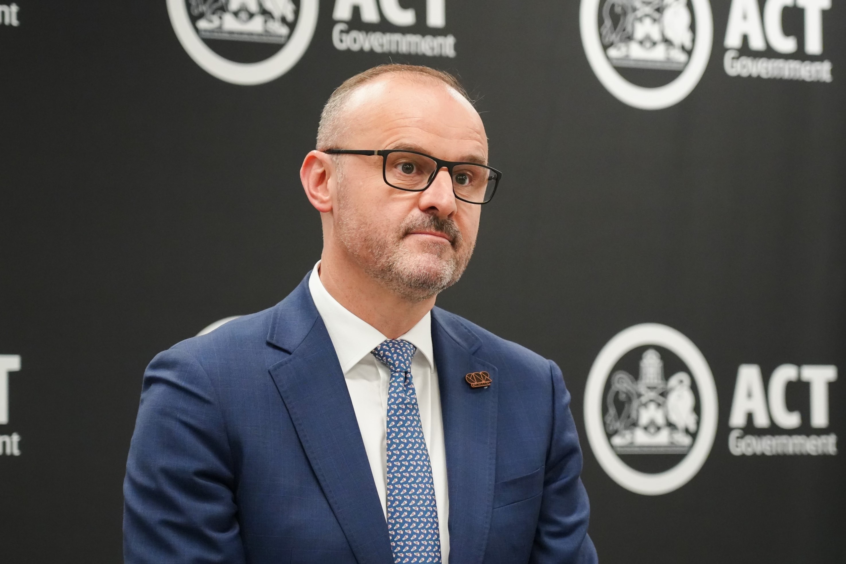 A man in a navy suit looking serious.
