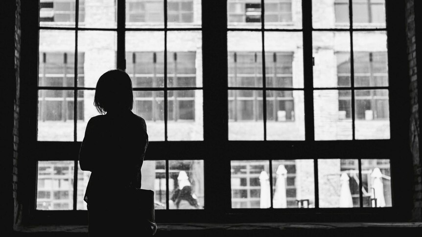 Silhouette of person inside in front of a window