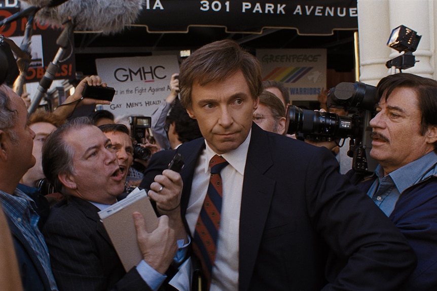 Colour still of Hugh Jackman surrounded by press in 2018 film The Frontrunner.