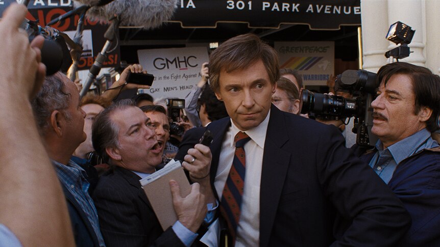 Colour still of Hugh Jackman surrounded by press in 2018 film The Frontrunner.