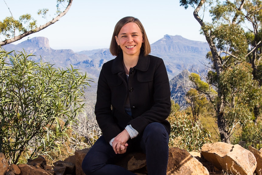 Astrophysicist Lisa Harvey-Smith sitting in front of landscape.