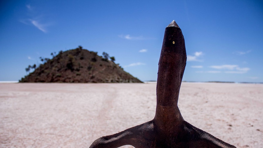 One of Sir Antony Gormley's sculptures at Lake Ballard, with Snake Hill in the background.