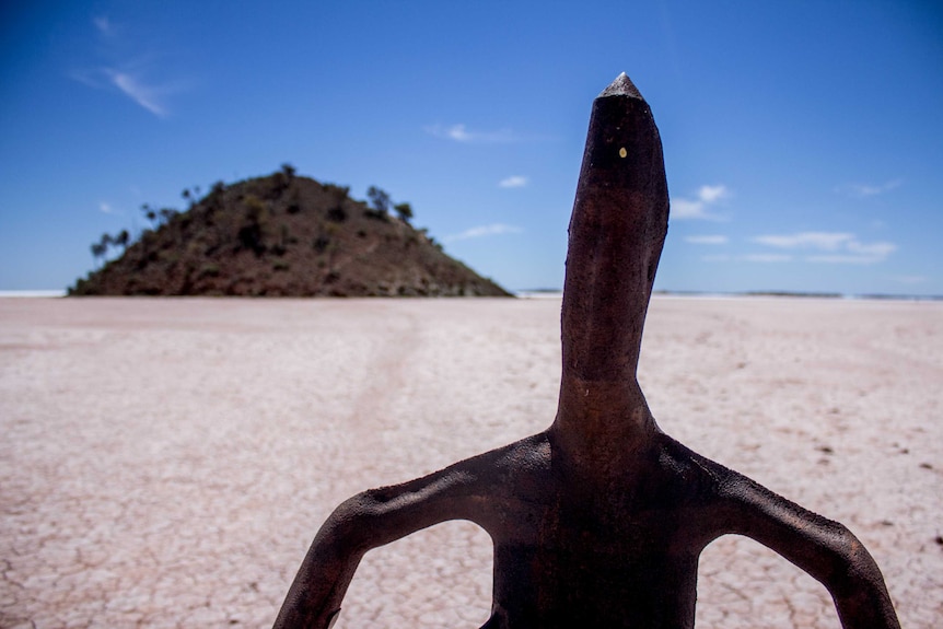 One of Sir Antony Gormley's sculptures at Lake Ballard, with Snake Hill in the background.