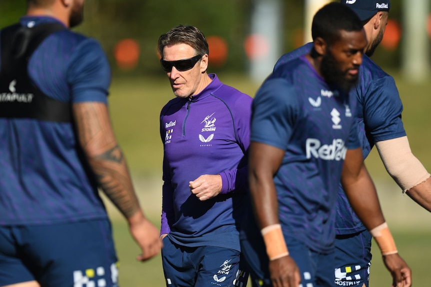 A coach surrounded by rugby league players