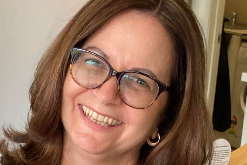 A smiling woman with brown hair and glasses