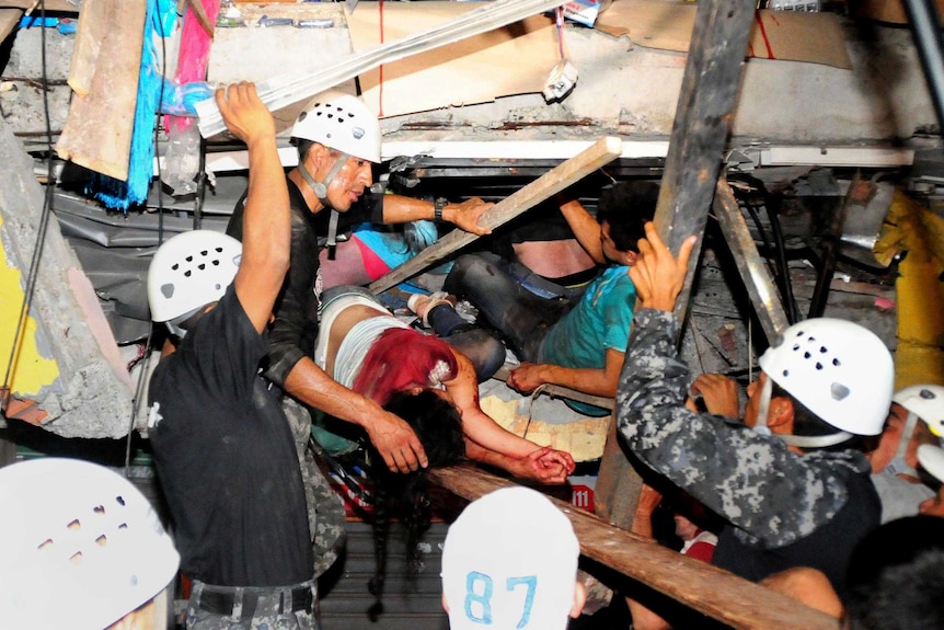 A survivor of the earthquake is pulled from the rubble on a stretcher by rescue workers.