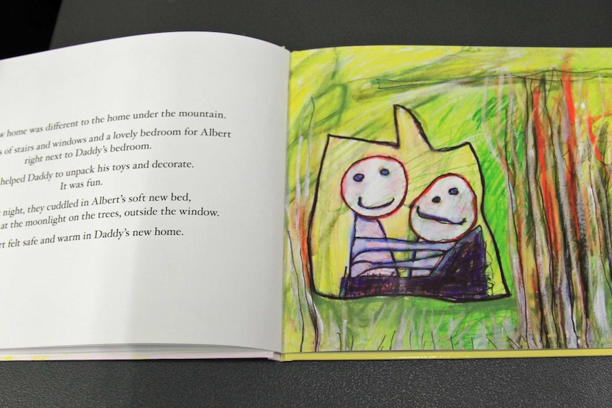 Childrens book open showing a page of text and a drawing by three-year-old Albert