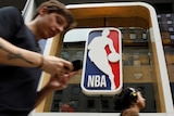 A man walks past a large NBA logo.