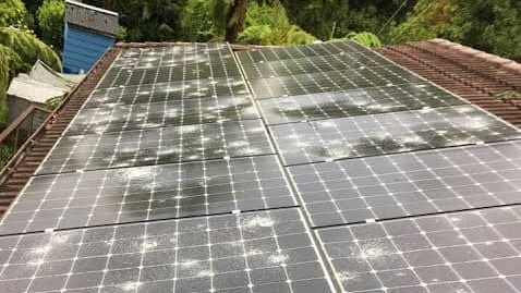 Solar panels on a rooftop are cracked from falling hail.