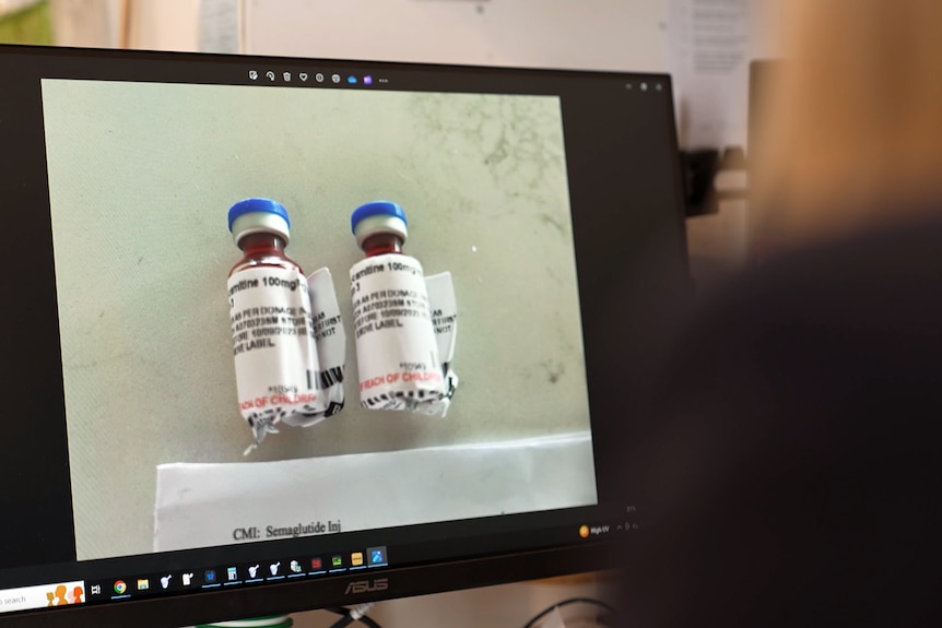 电脑屏幕上的一张照片显示两个小瓶，上面贴着药物标签，里面装满了红色液体。