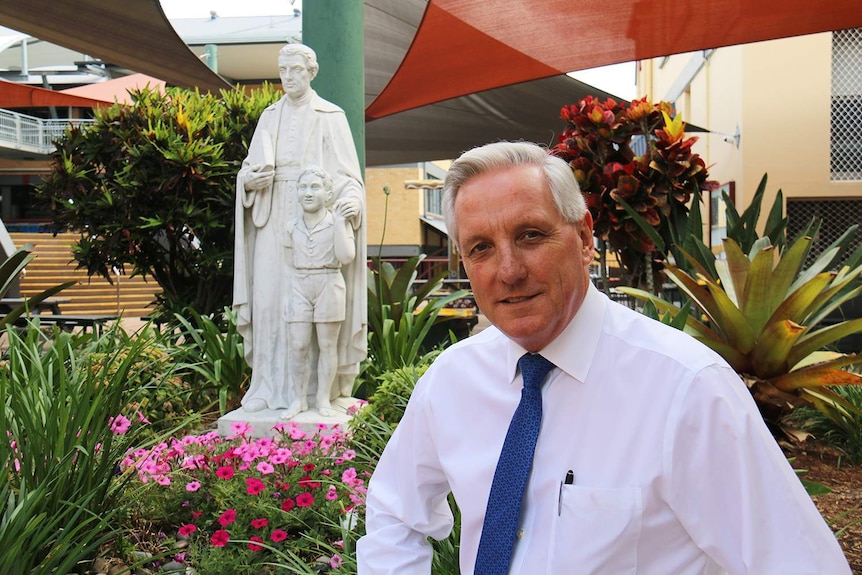 St James College principal Gerry Crooks sits in the garden near a statue at the school.