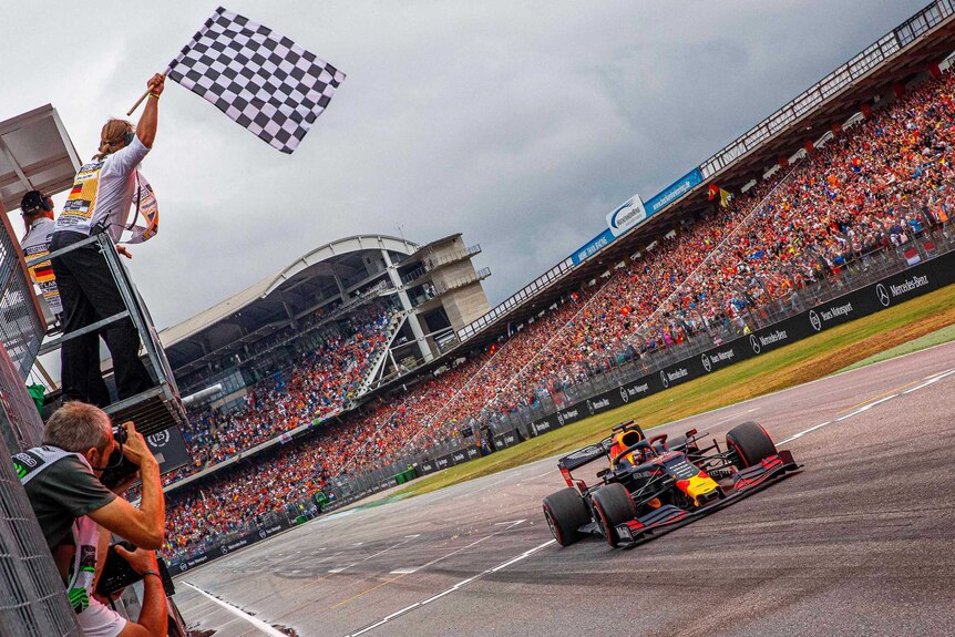 An official at trackside waves the checkered flag as a F1 driver crosses the line to win.