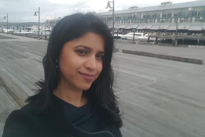 A woman standing in front of a wharf.