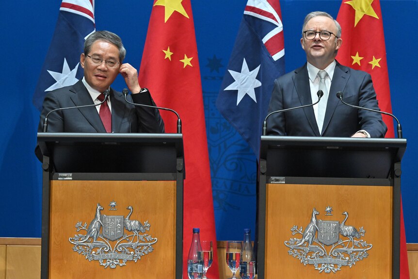 Li Qiang and Anthony Albanese speaking at podiums in front of the China and Australian flags